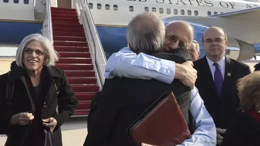Alan Gross embraces Tim Rieser on the tarmac as he disembarks from a U.S. government plane with wife Judy.