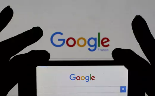 A woman holds her smart phone which displays the Google home page, France.