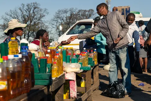 A customer buys cooking oil at a stall in Harare.