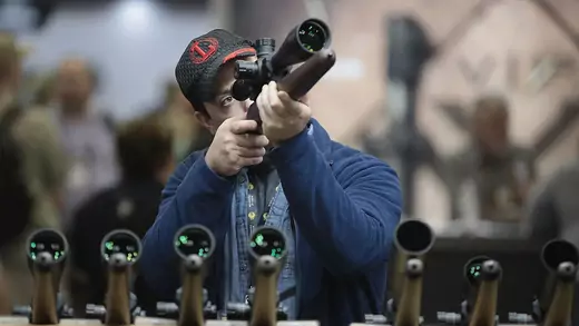 A gun enthusiast looks at a rifle scope