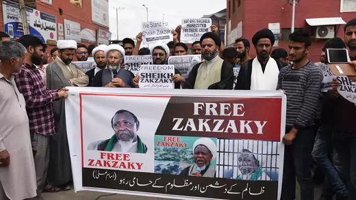 Protesters hold a sign that says "Free Zakzaky" and has images of the Nigerian Shia leader.