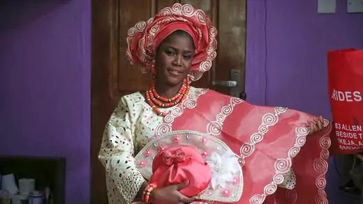A Nigerian bride shows off her pink and white wedding dress and clutch.