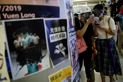 Protesters check their phones as they take part in a protest inside the Yuen Long MTR station