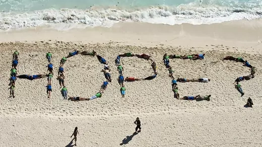 Environmental activists lay on a beach and spell out 'Hope?' with their bodies.