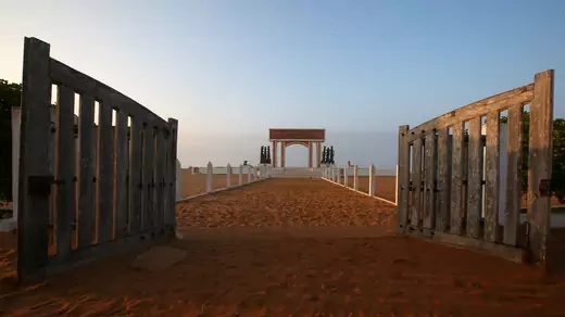 A gate stands open on the beach.