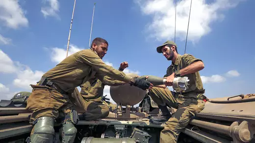 Israeli soldiers charge a mortar shell