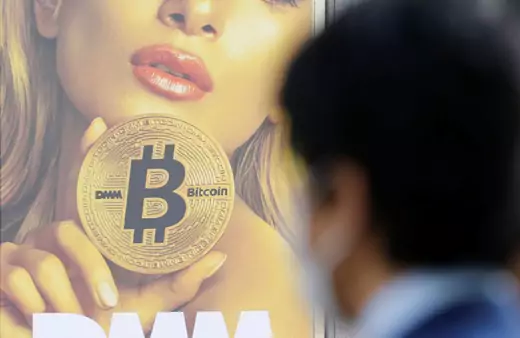 A man stands near an advertisement of a cryptocurrency exchange in Tokyo, Japan.