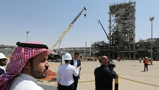 People stand in front of a damaged oil facility in Saudi Arabia. 