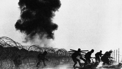 Iranian troops advance on an Iraqi-held position in the Majnoon Islands on March 10, 1984, as Iraqi armored vehicles burn in the background.