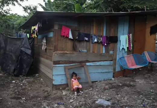 A child sits outside her home in San Pedro Sula, Honduras.
