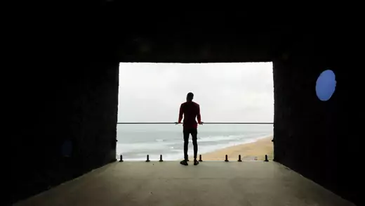 A man looks out at the sea from a building 