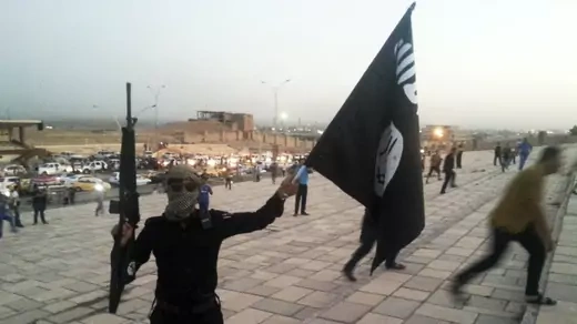 An Islamic State fighter holds a flag bearing the group's symbol on the streets of Mosul, Iraq, on June 23, 2014.  