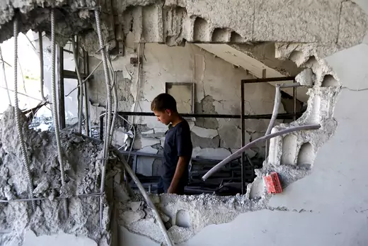 A child inspects a site hit by what activists said was an airstrike by forces loyal to Syria's President Bashar el-Asaad at Arbin town in Damascus countryside, Syria July 21, 2015.