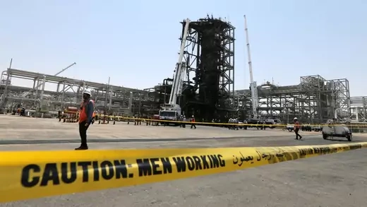 Workers at the damaged site of a Saudi Aramco oil facility.