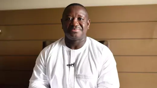 President Julius Maada Bio sits with his hands clasped at a desk.