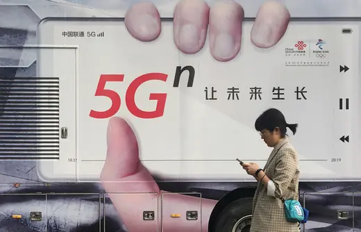 A woman using her mobile phone walks past a vehicle covered in a China Unicom 5G advertisement in Beijing, China September 17, 2019.