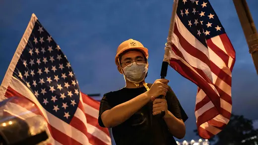 A protester in Hong Kong wears a face mask and holds an American flag.