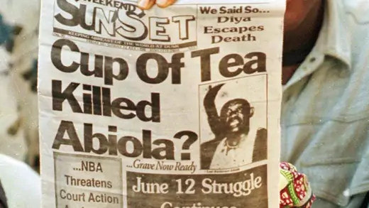 A supporter of Chief Mashood Abiola holds up a newpaper during a demonstration outside the family home July 10 to protest about the suspicious nature of his death.