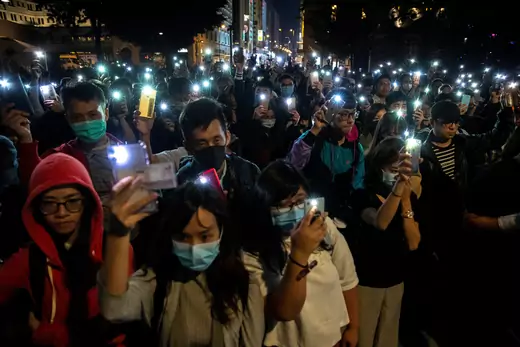 Protesters raise mobile phones as they gather to show support for protesters inside the Hong Kong Polytechnic University (PolyU) campus, November 19, 2019