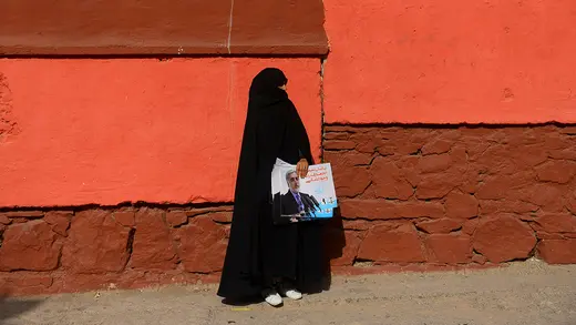 An Afghan woman carries posters of presidential candidate Abdullah Abdullah ahead of elections set for September 2019.