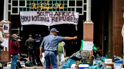 South African Police officer gestures as they forcefully remove refugees from various countries who were camping outside the Cape Town offices of the United Nations Council for Refugees, In Cape Town on October 30, 2019.