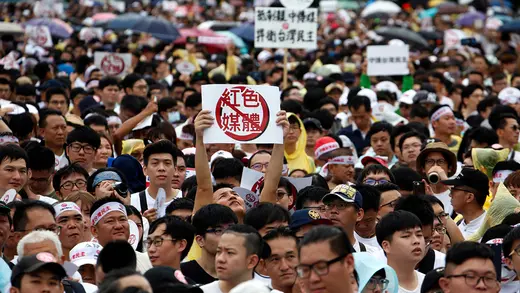 People hold signs in Taipei that read "reject red media" during a protest against pro-China media.