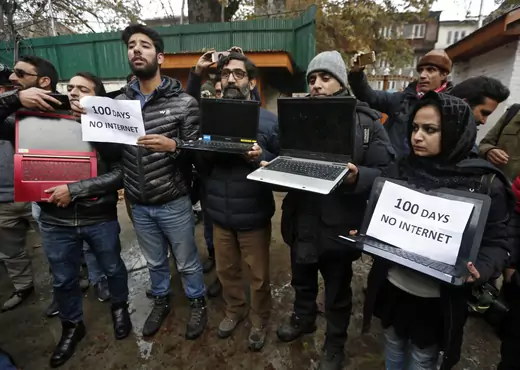 Kashmiri journalists display laptops and placards during a protest demanding restoration of internet service, in Srinagar