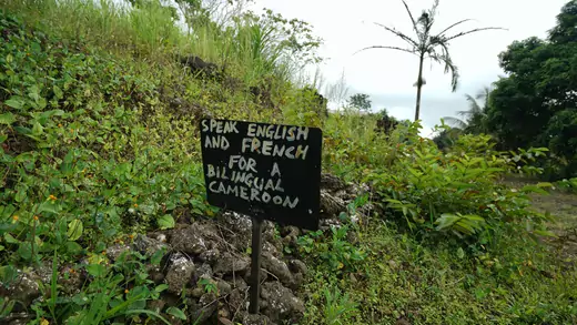 A sign saying " Speak English or French for a bilingual Cameroon" outside a now abandoned school in rural southwest Cameroon, on May 22, 2019.