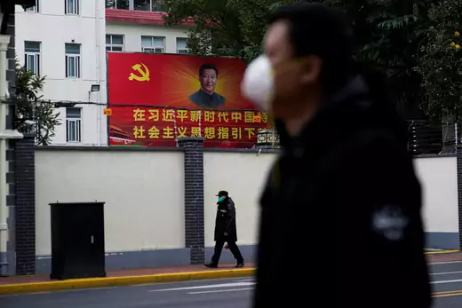 People wearing masks walk past a portrait of Chinese President Xi Jinping on a street as the country is hit by an outbreak of the novel coronavirus in Shanghai.