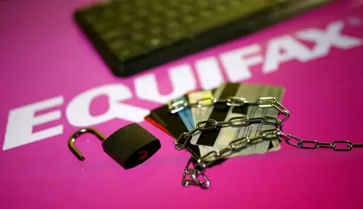 Credit cards, a chain and an open padlock is seen in front of displayed Equifax logo