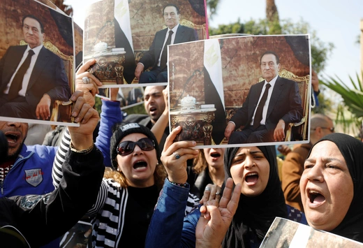 Supporters of former Egyptian President Hosni Mubarak hold his photos near the main gate of a cemetery during his burial ceremony, east of Cairo, Egypt February 26, 2020.