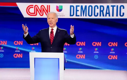 Former Vice President Joe Biden gestures forward as he stands behind a podium at the March 15 Democratic primary debate in Washington, DC.