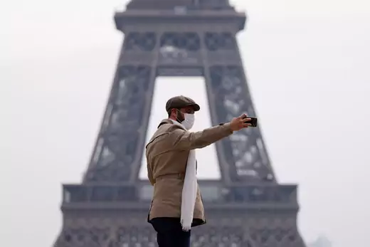 A man wearing a protective face mask makes a selfie in front of the Eiffel tower in Paris as a lockdown imposed to slow the rate of the coronavirus disease (COVID-19) contagion started at midday in Paris, France.