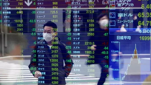 A pedestrian wearing a protective face mask amid the the coronavirus (COVID-19) outbreak is reflected on a screen displaying stock prices outside a brokerage in Tokyo, Japan, on March 17, 2020. 