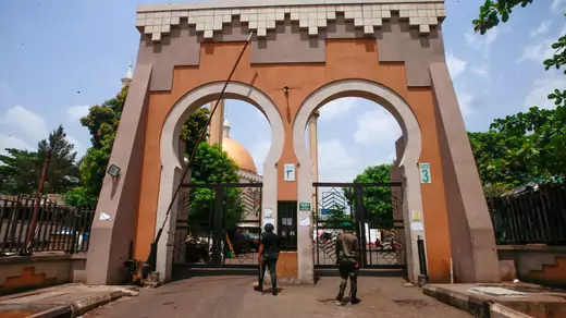 Two policemen are seen at the gate of the Abuja National Mosque, as the spread of the coronavirus disease (COVID-19) continues in Abuja, Nigeria, on March 27, 2020. The mosque's dome and minarets can be seen through the gate in the background.