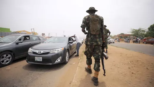 A soldier carrying a rifle in military fatigues observes temperature checks at the border between Abuja and Nasarawa states in Nigeria, as the authorities try to limit the spread of the coronavirus disease (COVID-19), on March 30, 2020. 