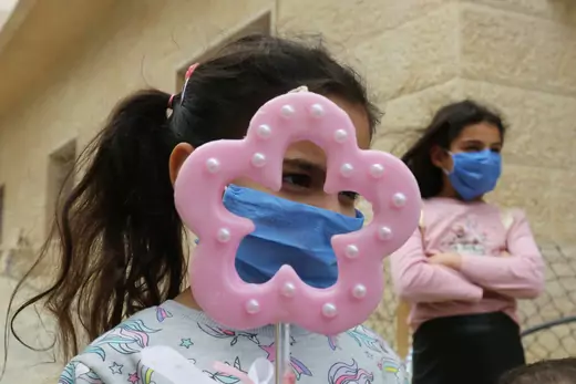 Girls wearing face masks and one of them holds a candle as they wait for the blessing of a priest roaming neighbourhoods to celebrate Palm Sunday, amid the lockdown to contain the coronavirus disease (COVID-19), in Marjayoun, southern Lebanon.