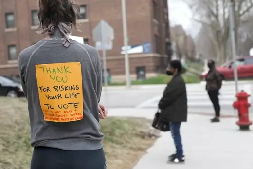Voter Rachel Messenger wears a sign reading "Thank you for risking your life to vote" as she waits in line outside Riverside University High School to cast a ballot during the presidential primary election held amid the coronavirus disease (COVID-19) outbreak in Milwaukee, Wisconsin.