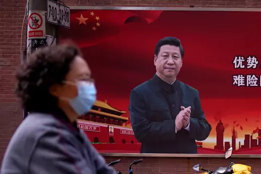 A woman wearing a protective mask is seen past a portrait of Chinese President Xi Jinping on a street as the country is hit by an outbreak of the coronavirus, in Shanghai, China.