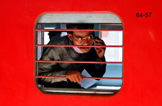 Man on cell phone looking out train window