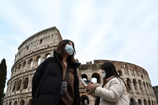Tourists wearing protective respiratory masks tour outside the Colosseo monument (Colisee, Coliseum) in downtown Rome.