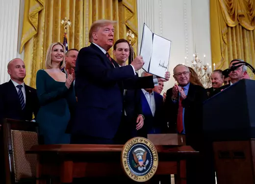 President Donald J. Trump holds up an executive order in front of a crowd at the White House. 