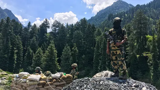 A soldier stands on a pile of rocks in a mountainous region along the China-India border. 