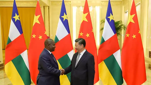 Chinese President Xi Jinping shakes hands with Central African Republic President Faustin-Archange Touadera in front of a row of tall flags