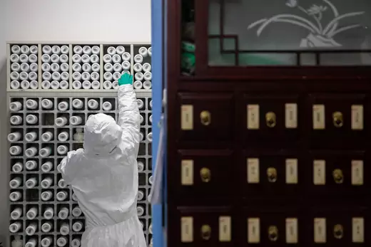 A medical worker in protective suit prepares traditional Chinese medicine (TCM) for patients of the novel coronavirus with an intelligent dispensing equipment at a pharmacy in Wuhan, China on March 2, 2020.