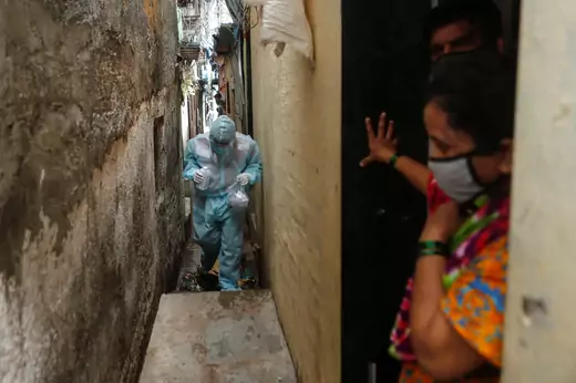 A health worker in PPE walks through an alleyway