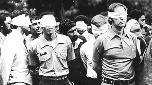 A group of American hostages in Iran stand blindfolded and handcuffed amid their captors