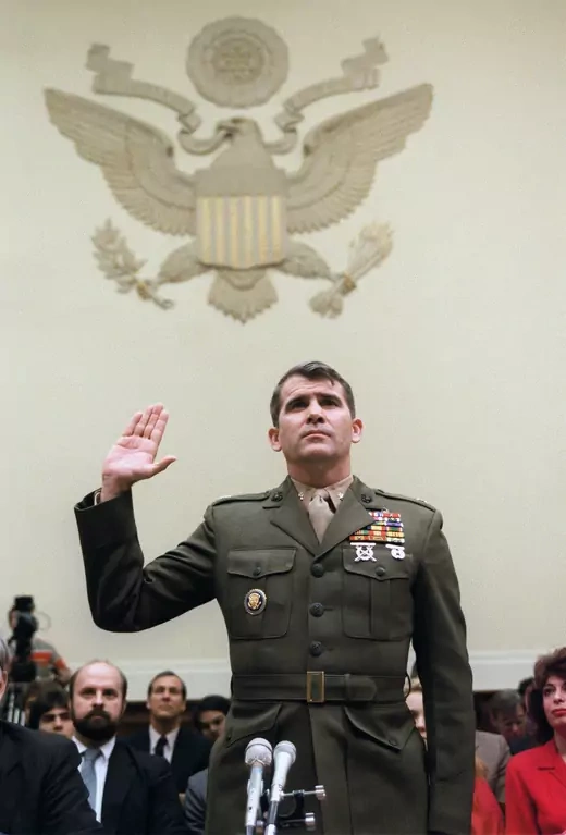 Oliver North, in his military uniform, holds up his hand to be sworn in
