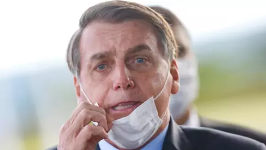 Brazilian President Jair Bolsonaro adjusts mask.