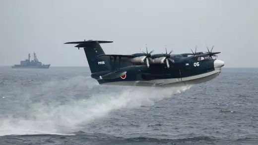 A Japanese Maritime Self-Defense Force seaplane takes off during a naval fleet review. 